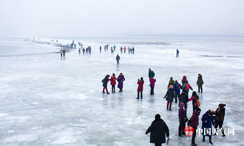 近日，辽宁遭遇寒潮，各地气温屡创入冬新低。13日，锦州笔架山渤海海域海水结冰，船只被海冰封冻。适逢周末，冰封的大海吸引了众多市民前来观看，大家顺着冰路一边游玩一边跨海向距离1.8公里外的笔架山岛走去。